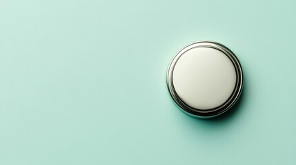 Round, white button with metallic rim on mint green background