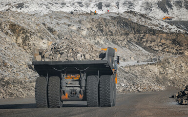 Heavy machinery in open pit coal mine during winter, back view