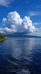 Landscape view of blue ocean under sky with clouds, distant shore and mountain