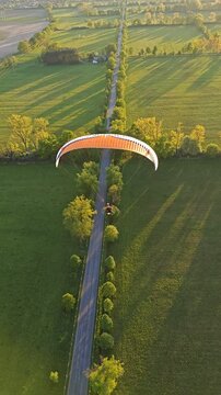 PARAGLIDING aerial panorama of motor-powered paragliding pilot flying above land with engine unit and colorful wing in scenic sky view over meadows and lakes in the countryside	
