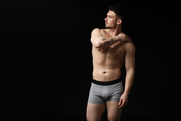 Fototapeta premium Young man in stylish light grey underwear on black background. Space for text