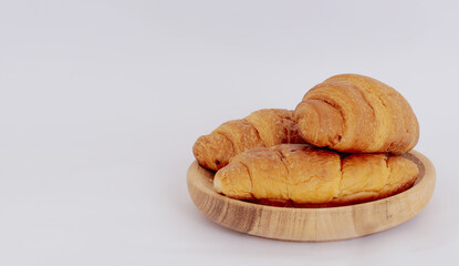Wooden plate with tasty croissants isolated on white background.