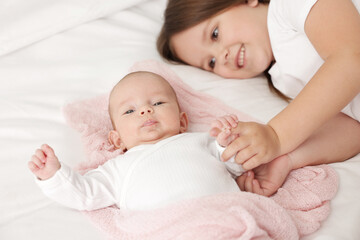 Cute girl and her little sister on bed at home, selective focus