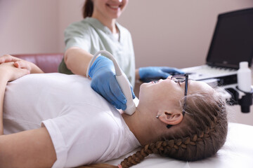 Sonographer conducting girl's thyroid gland ultrasound examination in clinic, closeup