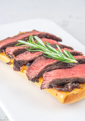 Grilled ciabatta sandwich with melted cheese, juicy steak, caramelized onions, and rosemary