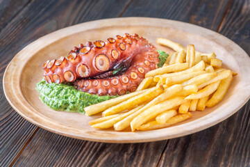 Baked Octopus With Creamy Spinach And Fries On A Rustic Plate