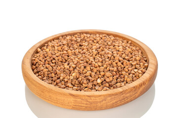 Raw buckwheat in a wooden plate isolated on a white background, macro.