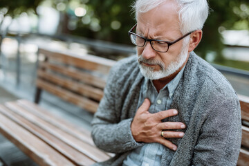 Myocardial infarction cardiac arrest diagnosis recovery. Chest pain treatment. Blood clot medical imaging. Elderly man experiencing discomfort on a park bench