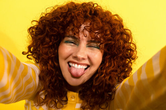 Playful woman looking at camera with curly hair making a silly face