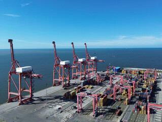 Aerial photo of Belawan Port, Medan, Indonesia, featuring large container cranes, stacked cargo...