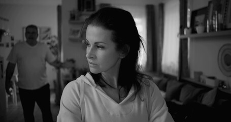 Obraz premium Woman turning away from man during heated argument, looking distant and upset, while man gestures in frustration in the background, capturing emotional tension and conflict