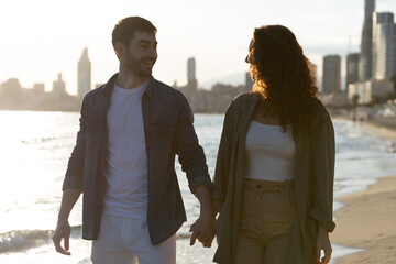 Couple holding hands and smiling on beach at sunset. Lifestyle. Vacations.