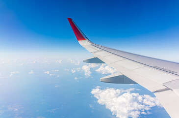 Fototapeta premium View from the airplane window at a beautiful cloudy sky and the airplane wing