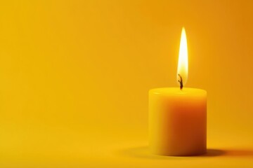Close-up of burning yellow candle on yellow backdrop, close-up, birthday party
