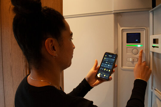Woman connecting smart phone app with thermostat at home