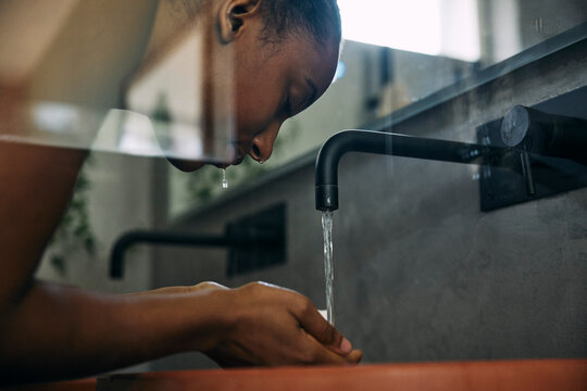 Low angle view of woman washing face with faucet water in bathroom