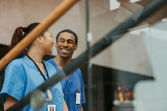 Happy male and female wearing medical scrubs talking with each other
