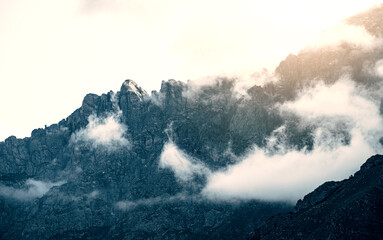 Majestic mountain peaks covered with dramatic mist and sunrise light. Travel, nature and abstract concepts.