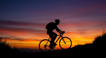 Fototapeta premium Silhouette of a cyclist riding a bike at sunset with colorful sky