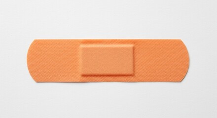 Obraz premium Adhesive Bandage on White Background - A single orange adhesive bandage isolated on a white background. Perfect for medical, healthcare, or first aid related projects