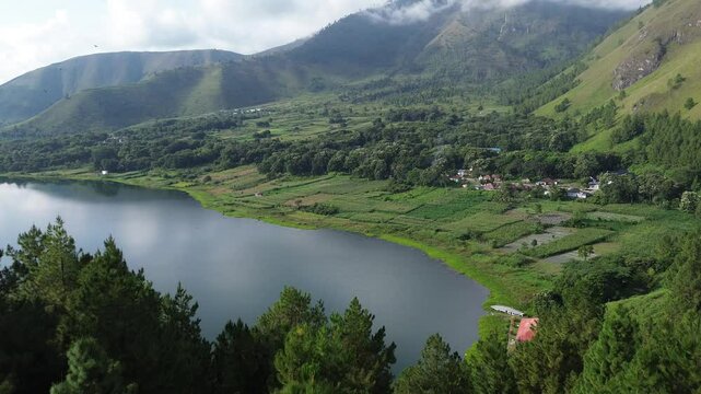 Aerial view of a peaceful lakeside village in Samosir, located on Lake Toba, North Sumatra, Indonesia. Surrounded by lush green hills and calm waters