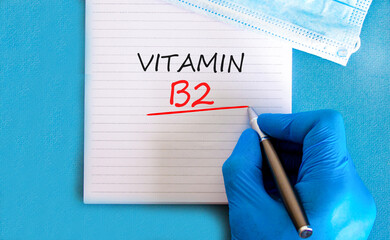 Vitamin B2 riboflavin symbol. Concept words Vitamin B2 on beautiful white note. Doctor's hand in...
