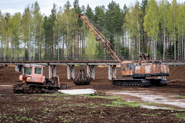 Abandoned Soviet Bulldozer and Rusty Crawler Crane at Peat or Soil Processing Plant – Vintage...
