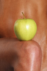 A green apple balanced on a woman's leg