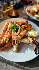 Cooked seafood in a plate, restaurant. Crustaceans with sauce and lemon. Tasty and healthy food. Beautiful presentation of a seafood dish. Large shrimps, langoustine