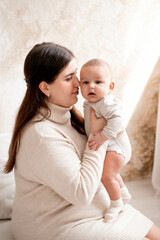 a mother with a baby, a mom holding her son's little child in her arms, hugging and kissing him, maternal love and care, mother and child