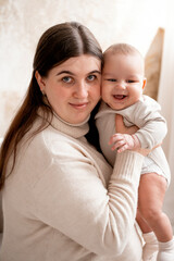 a mother with a baby, a mom holding her son's little child in her arms, hugging and kissing him, maternal love and care, mother and child