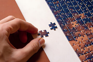 Hand Holding Puzzle Piece Completing Jigsaw on Table – Problem Solving Concept