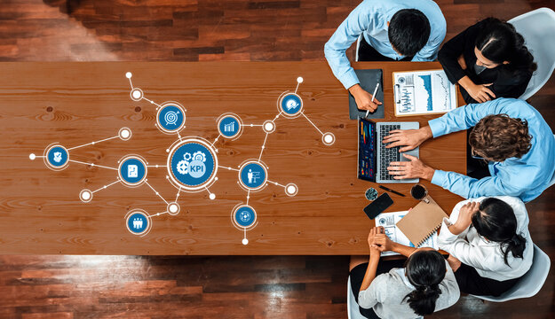 A diverse team collaborates in a modern office setting, focusing on KPI analysis and strategic planning using digital tools and data visualization techniques. Amity