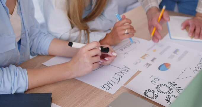 Group of business people in office discussing reports, hands close-up. Office workers make up a marketing strategy. Concept collaborative marketing meeting, employee engagement, brainstorming