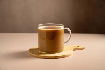 Frothy coffee cappuccino with milk in transparent glass mug 