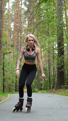 Attractive blonde feels free and light while rollerblading in city park in summer. Stunning...