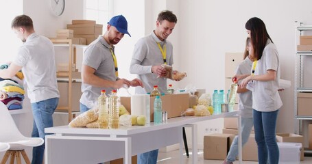 Group of positive volunteers working together at an aid center, packing food boxes. Community service, donations, and charitable work, showcasing dedication to helping those in need.