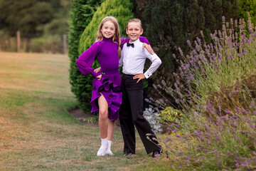 Elegant young boy and girl in ballroom dance attire performing outdoors. This juvenile dance couple captures grace, discipline, and youthful passion in a natural, outdoor setting. Ideal for themes rel