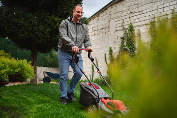 Man enjoys mowing the lawn in a vibrant garden during a sunny afternoon in suburban neighborhood
