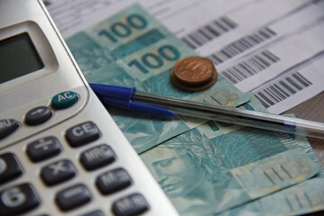 Real - Brazilian currency. Real notes on a wooden table with a calculator and pen in the...