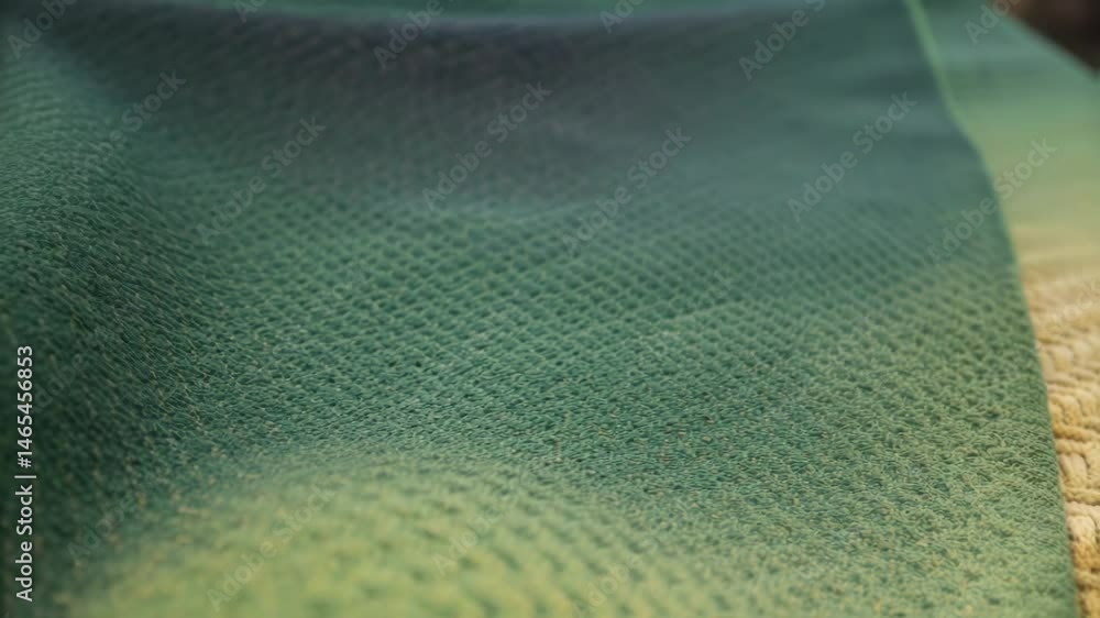 Poster a medium closeup of a hand gently touching a thermochromic fabric showcasing the intricate weave and