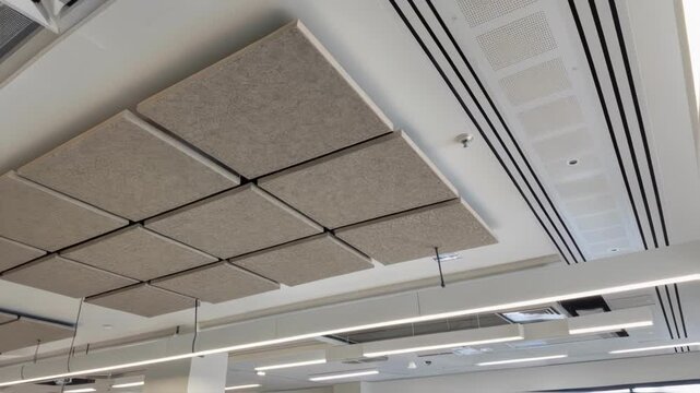 A medium closeup photograph of selfextinguishing acoustic panels suspended from a ceiling highlighting their dual function in sound dampening and fire safety compliance.