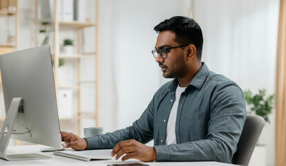 Asian male adult working at computer in modern office setting