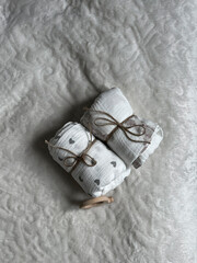 Two twisted muslin diapers and an elephant teether are lying on a milky-colored blanket. Children's...