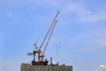 construction tower crane work with construction worker on top of building, used in construction site with blue sky.
