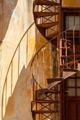 close up at steel rusted spiral staircase with shadows in Gythio, Greece