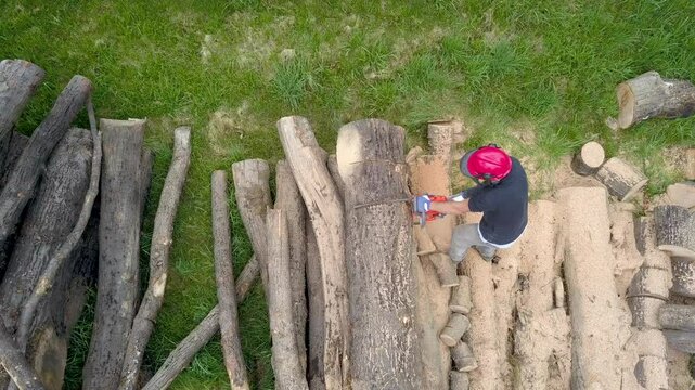 Lumberjack with a chainsaw cutting trees in the forest. Preparing firewood for winter. Top down view. Aerial view from drone
