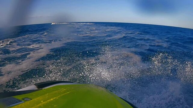 Dynamic POV footage of a yellow jet ski cutting through ocean waves with intense water splashes and thrilling turns on a bright sunny day. Captures the excitement of aquatic adventure, adrenaline spor