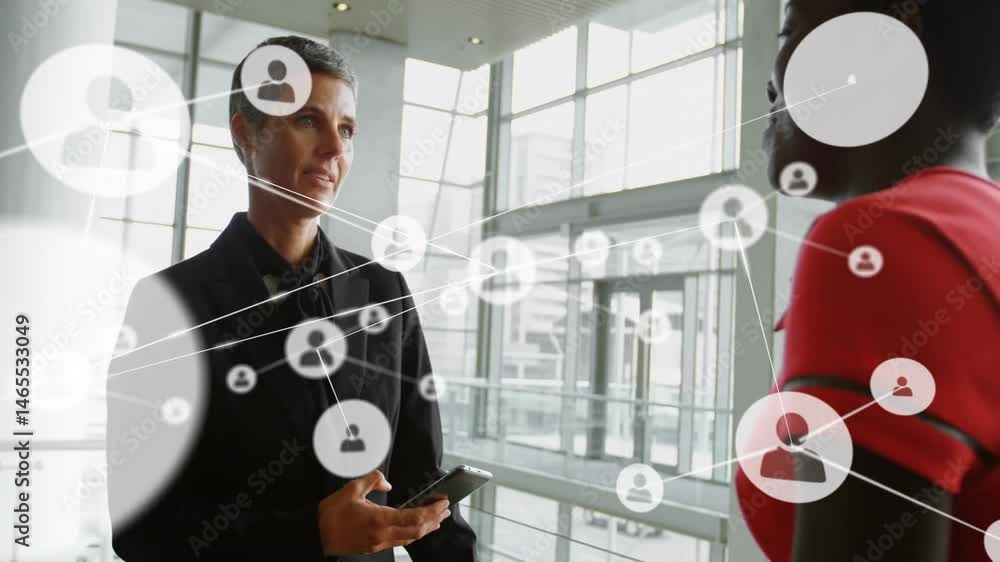 Poster senior manager using tablet talking with associate in business lobby showing floating network icons