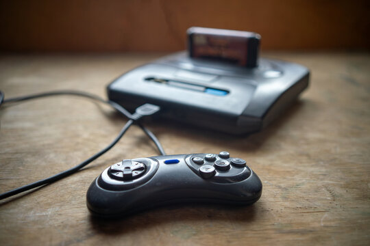 A vintage video game console with a connected gamepad.Games from the 90s.